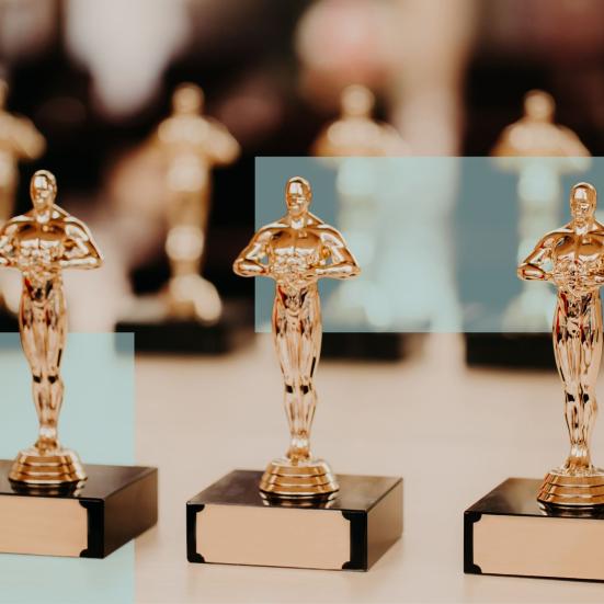 Tre prisstatuetter i forgrunden med flere lignende statuetter bagved.