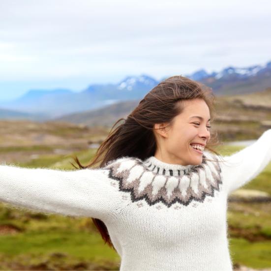 kvinde med hjemmestrikket trøje og bjerge i baggrunden