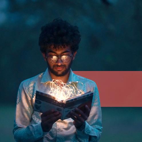 En ung mand læser i en lysende bog