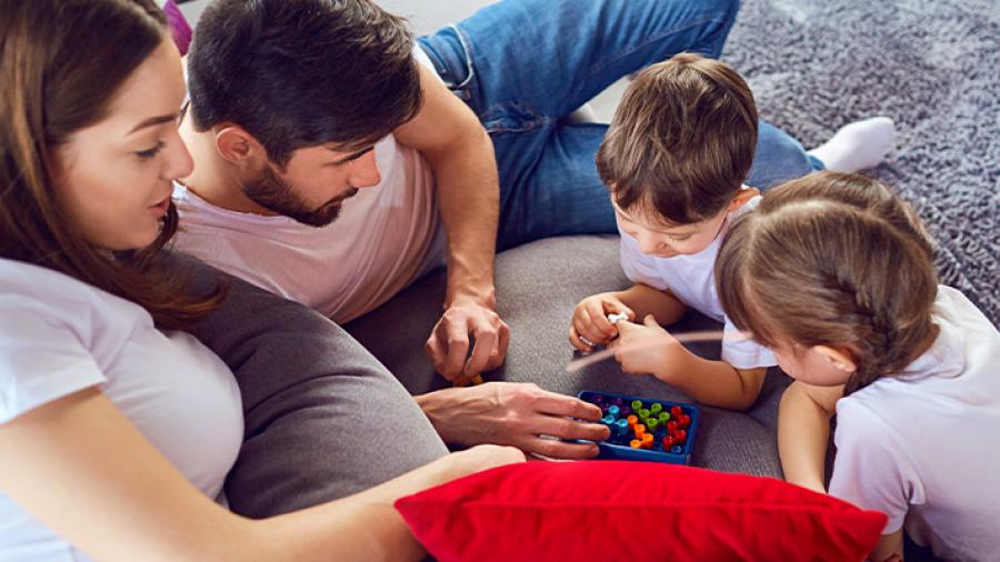 Mand, kvinde og to børn spiller brætspil