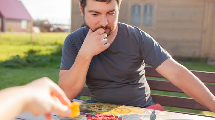 Mand sidder og tænker med et brætspil på bordet